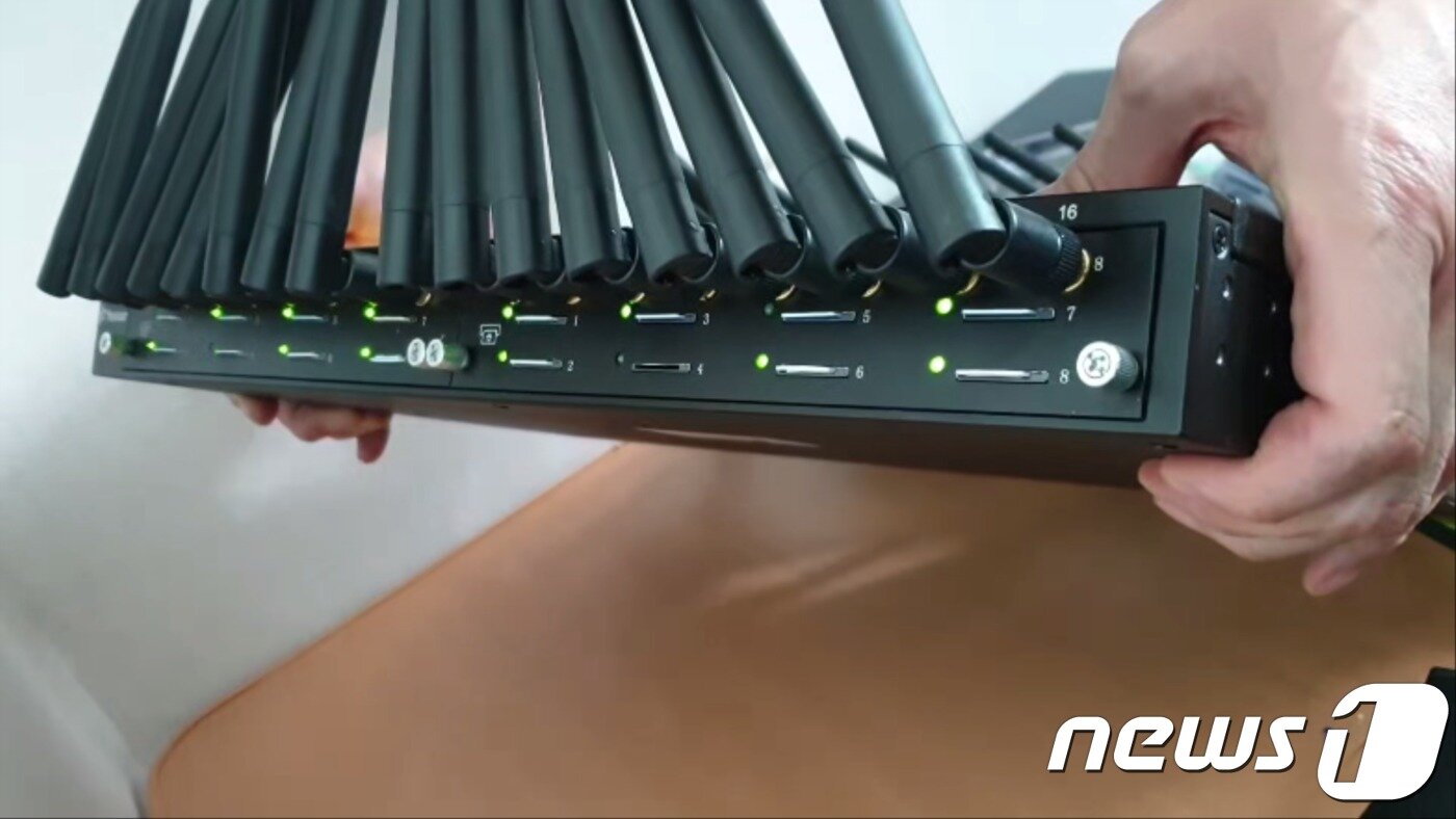 본문 이미지 - 지난해 12월 21일 경기도 부천시의 한 오피스텔에서 경찰은 발신 전화번호를 변조하는 중계기를 적발했다. 중계기 뒤에 있는 슬롯마다 유심칩이 꽂혀있고 초록색 램프가 깜빡이고 있다. 보이스피싱 콜센터가 중계기를 통해 국내 전화번호로 피해자들에게 연락하고 있다는 뜻이다.(부산지방경찰청 제공)ⓒ 뉴스1