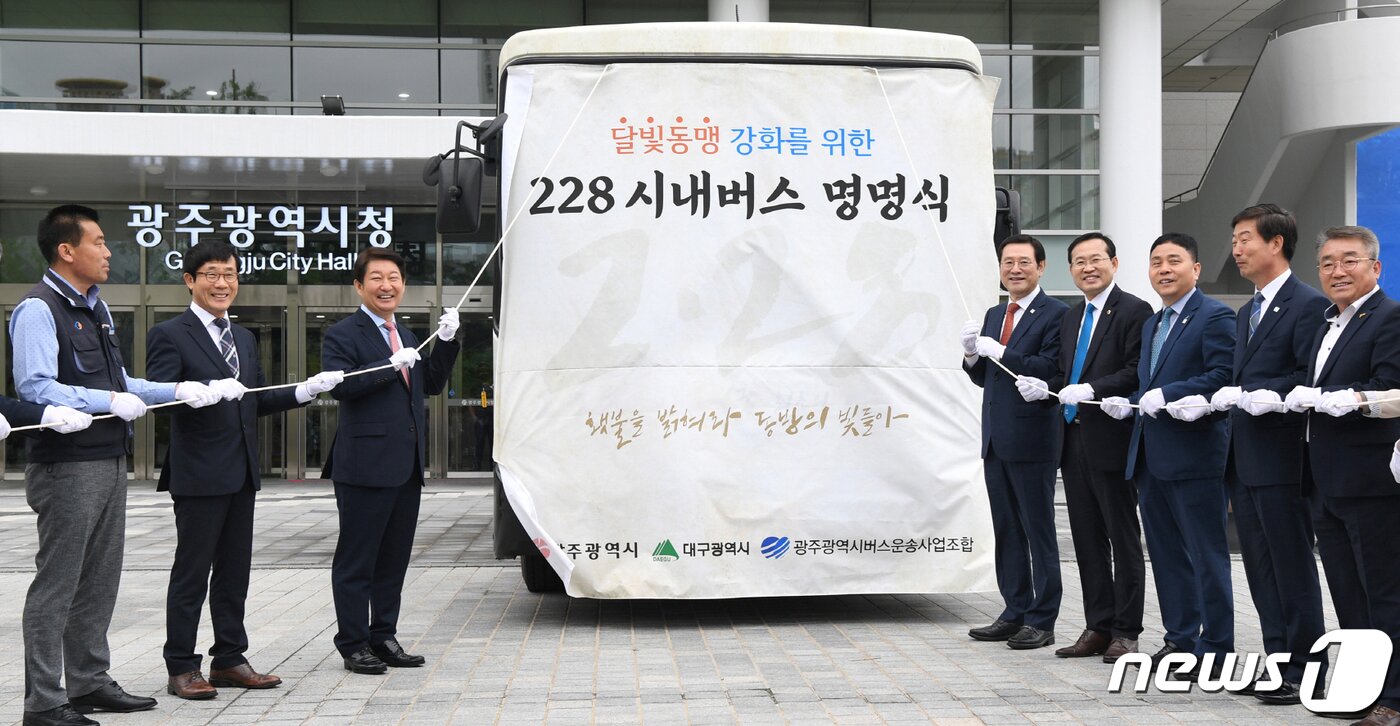 본문 이미지 - 이용섭 광주시장과 권영진 대구시장 등이 26일 광주시청 행정동 앞 광장에서 열린 광주·대구 달빛동맹 강화를 위한 '228버스 명명식'에 참석해 가림막 제거 세리머니를 하고 있다.(광주시 제공) ⓒ News1