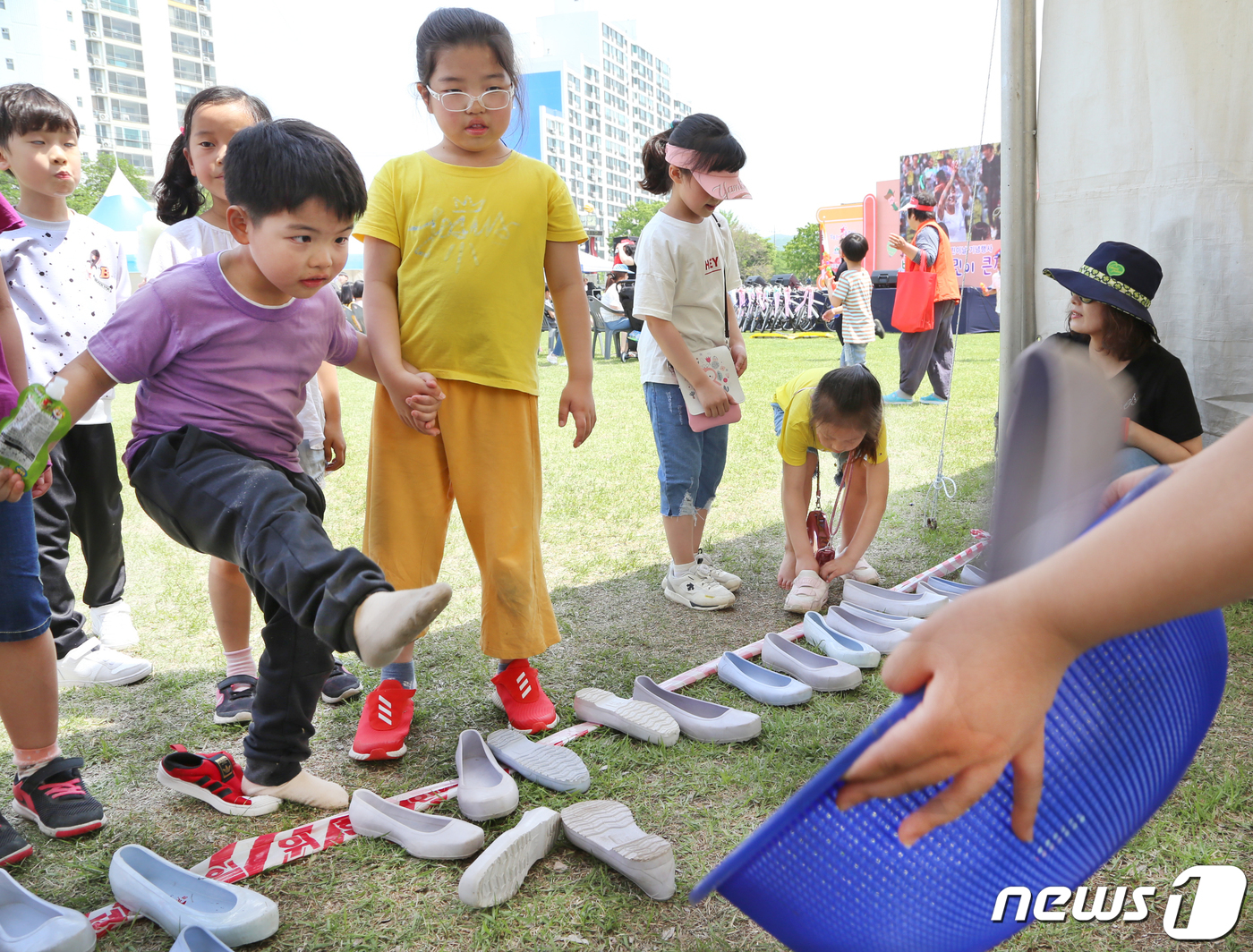 (성주=뉴스1) 정우용 기자 = 4일 경북 성주군 성밖숲에서 열린 '별고을 어린이 큰잔치'에서 한 어린이가 누나의 손을 잡고 발로 고무신 던지기 게임을 하고 있다.이날 열린 어린이 …