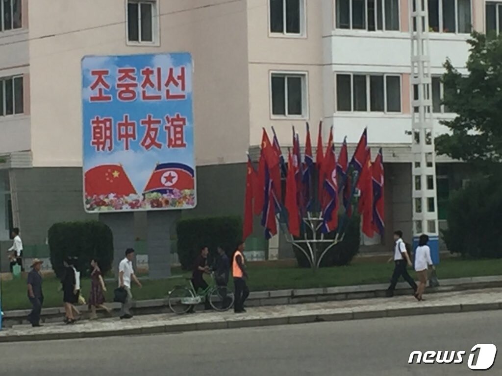 본문 이미지 - 지난 2019년 6월20일 시진핑 중국 국가주석의 북한 방문을 맞아 평양 시내에 ''조중(북중) 친선' 문구가 적힌 간판과 북한 인공기 및 중국 국기(오성홍기)가 설치돼 있다. (콜린 크룩스 북한 주재 영국대사 트위터) ⓒ 뉴스1