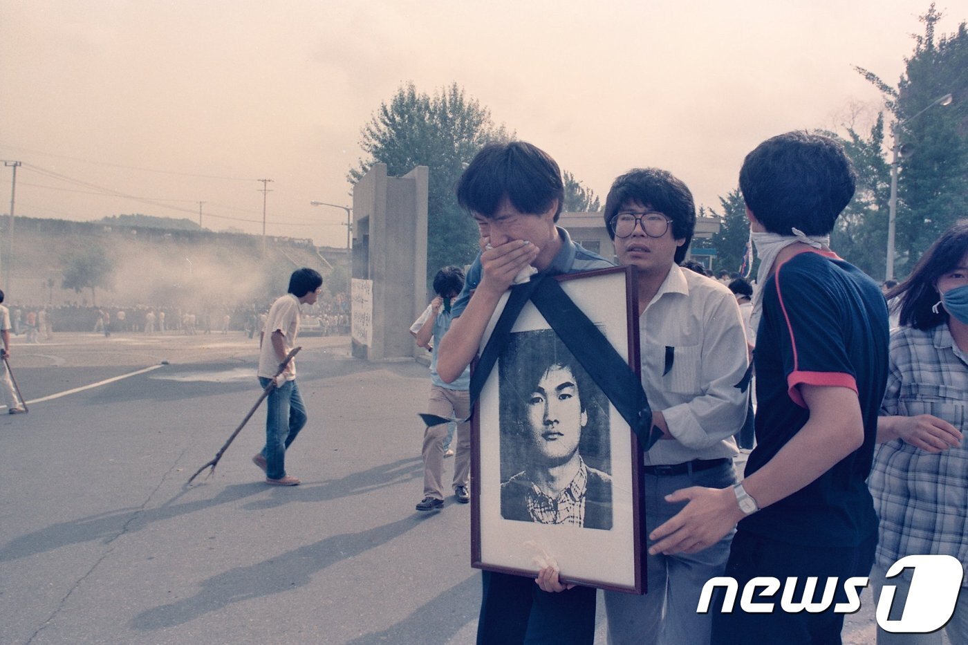 본문 이미지 - 1987년 7월9일 이한열 열사의 장례식 당시 이 열사의 영정 사진을 들고 울고 있는 우상호 당시 연세대학교 학생회장. (이한열 기념사업회 제공) ⓒ 뉴스1