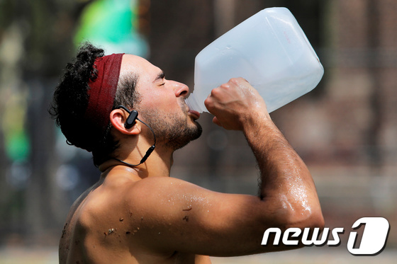 22일(현지시간) 미국 뉴욕 맨해튼에서 한 시민이 폭염에 견디기 위해 물을 마시고 있다. © 로이터=뉴스1