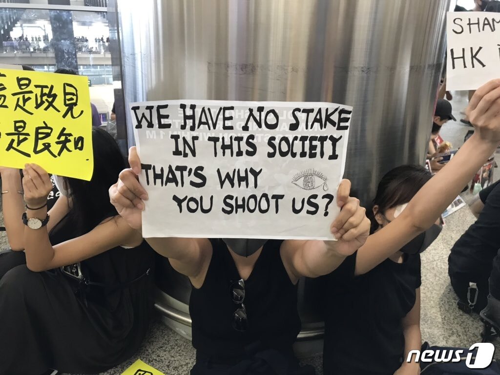 본문 이미지 - 12일 홍콩 국제공항을 점거한 한 시위 참가자가 &#34;우리는 이 사회에서 가진 게 없다. 그게 당신이 우리를 쏜 이유인가&#34;라는 종이를 들고 정부에 항의하고 있다.  &#40;미국 매체 쿼츠&#40;Quarz&#41;의 메리 후이 기자 트위터 계정.&#41; ⓒ 뉴스1