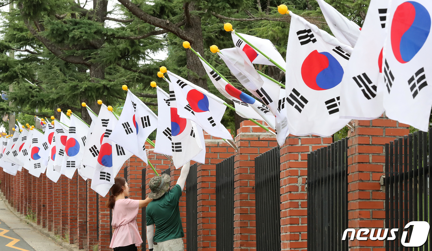 (대구=뉴스1) 공정식 기자 = 74주년 광복절을 하루 앞둔 14일 대구 동구 신암동 국립신암선열공원 직원들이 외곽 울타리를 따라 태극기를 걸고 있다.국립신암선열공원은 조국의 광복 …