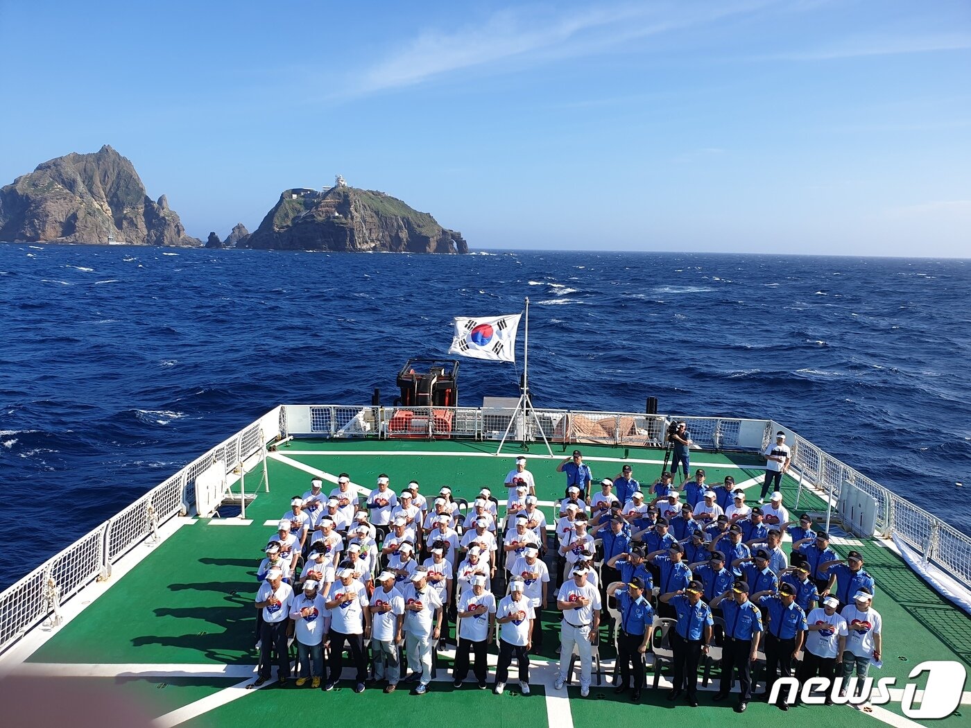 본문 이미지 - 74주년 광복절을 하루 앞둔 14일 해양경찰교육원 소속의 '바다로함'을 타고 독도 바다를 찾은 '독도 해양영토순례단'이 독도를 배경으로 함상 광복절 기념행사를 하고 있다. 이번 행사는 순국선열의 숭고한 정신을 되새기고 해양영토 수호 의지를 다지기 위해 실시됐으며 독립유공자 가족, 정책자문위원, 일반국민 등 130여명이 함께했다.(해경교육원 제공)2019.8.15  /뉴스1 ⓒ News1