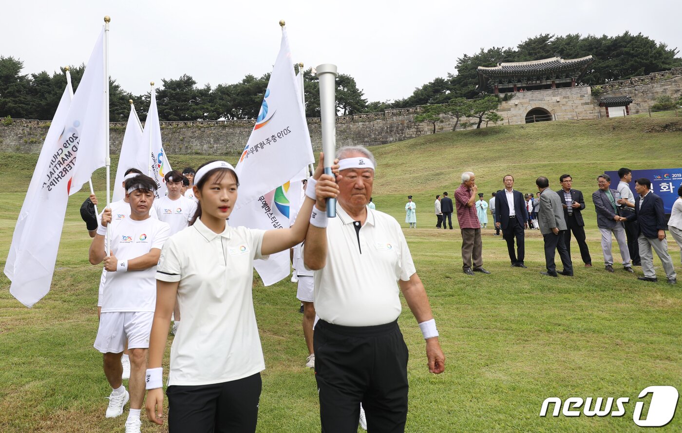 본문 이미지 - 28일 오전 충북 청주시 상당산성 남문에서 열린 2019충주세계무예마스터십 성화 채화식에서 성화봉송 첫 주자인 무예계 원로 강형원(81)씨와 차세대 무에타이 꿈나무 조은(17)양이 성화봉송을 하고 있다. 2019.8.28/뉴스1 ⓒ News1 김용빈 기자