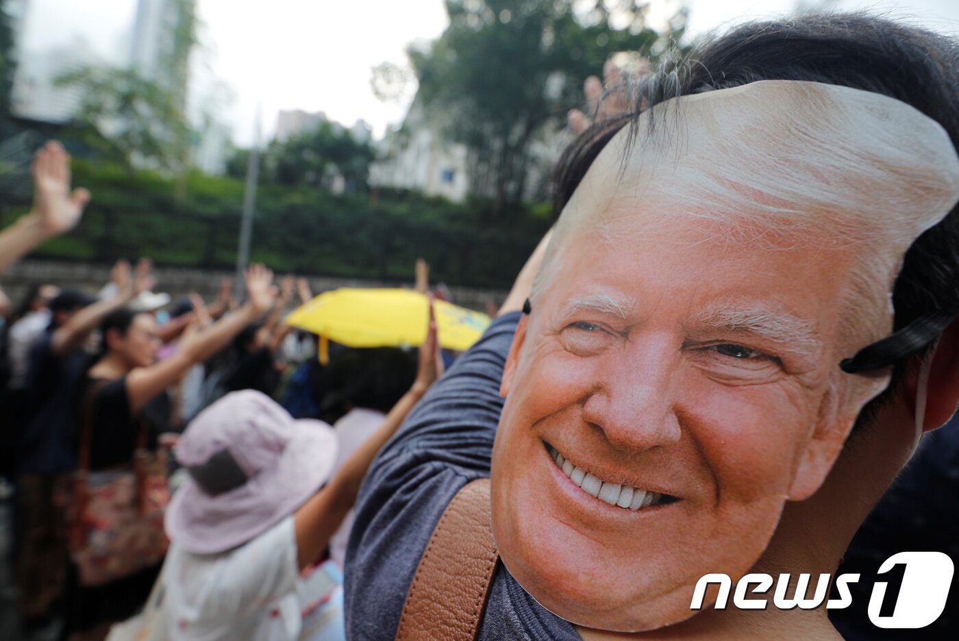 본문 이미지 - 한 시민이 트럼프 대통령의 가면을 쓰고 시위에 참여하고 있다. ⓒ 로이터=뉴스1