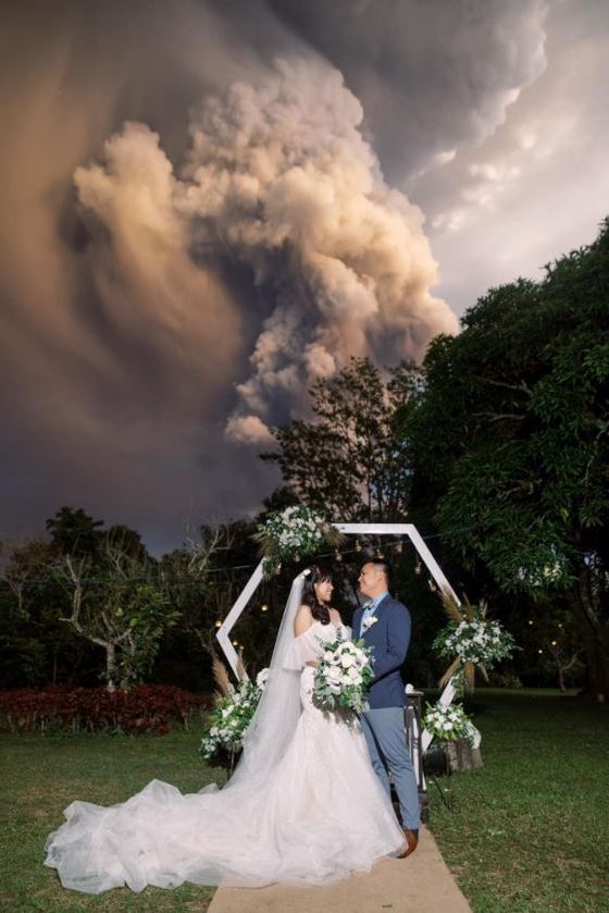 12일 화산재를 분출하는 탈 화산을 배경으로 결혼식을 올린 치노 배플러·캣 배플러 부부.<출처=CNN, 랜돌프 에번 트위터>© 뉴스1