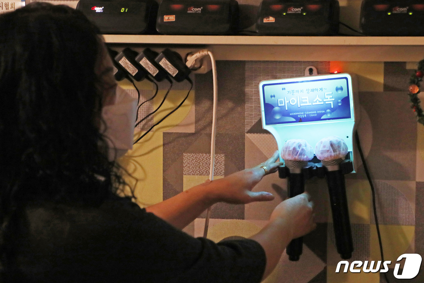 (성남=뉴스1) 조태형 기자 = 사회적 거리두기가 기존 2단계에서 1단계로 하향 조정된 12일 오후 경기도 성남시내 한 노래연습장에서 업주들이 영업 재개를 위한 준비를 하고 있다. …