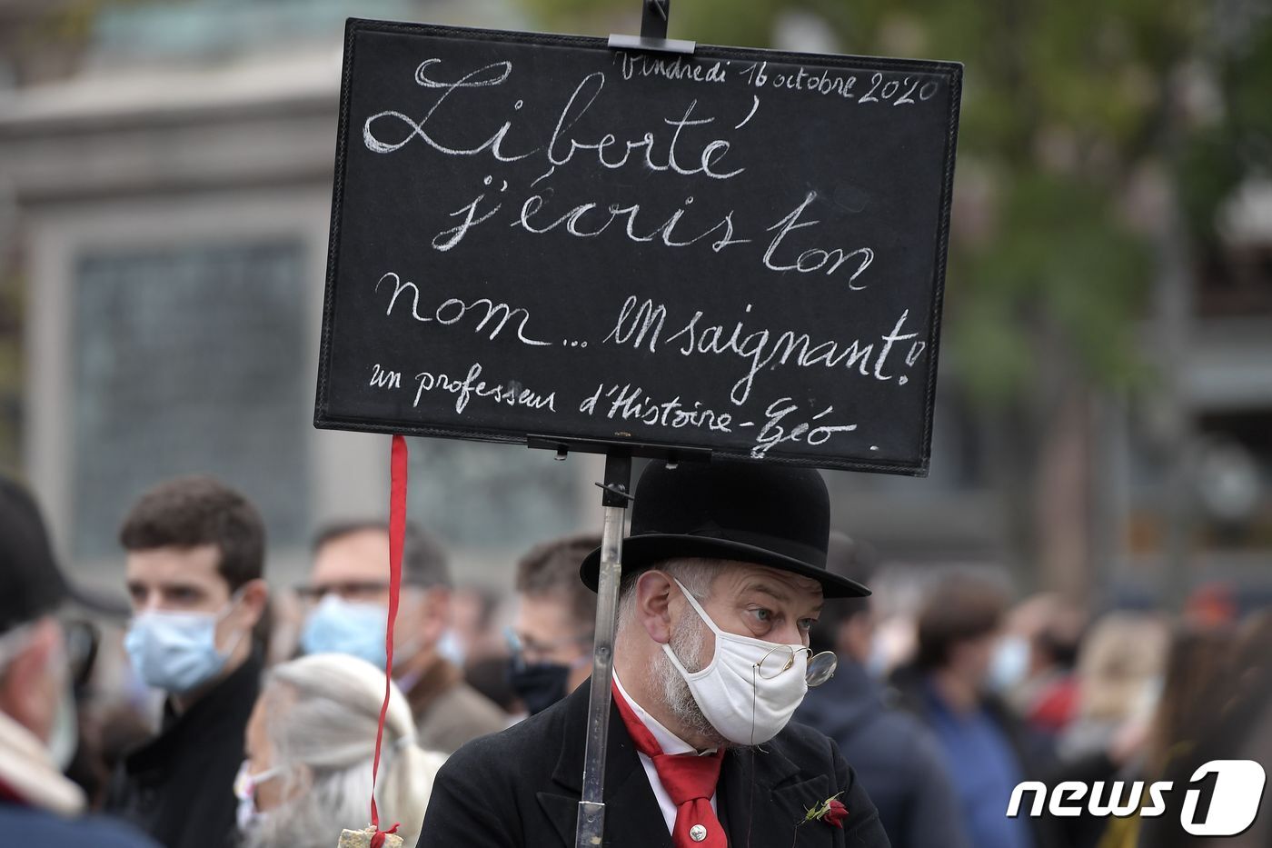 본문 이미지 - 18일(현지시간) 프랑스 스트라스부르에서 열린 '교사 참수사건' 추모 집회 참석자가 "자유, 난 피로써 당신의 이름을 쓴다"는 문구가 적힌 팻말을 들고 있다. ⓒ AFP=뉴스1