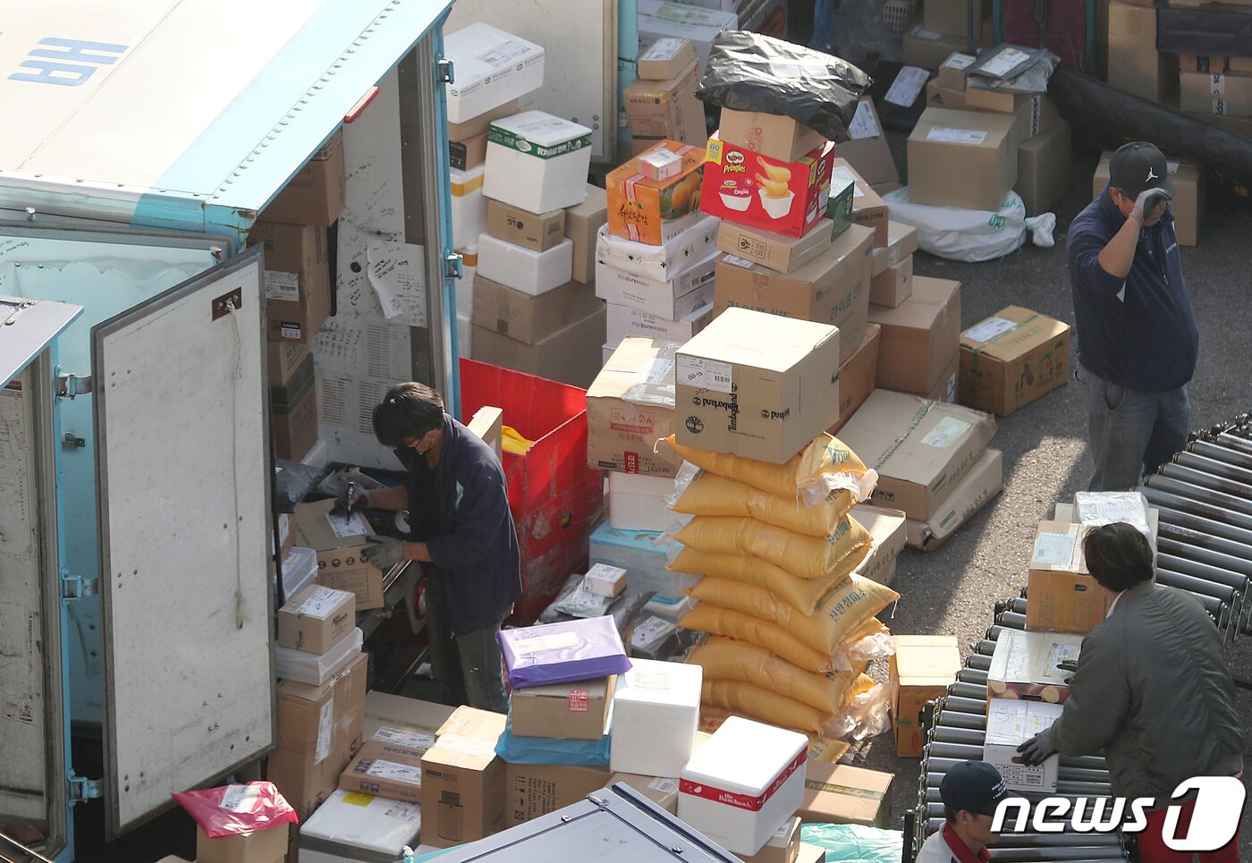본문 이미지 - 서울의 한 택배 물류센터에서 작업자들이 산더미처럼 쌓인 택배 박스를 나르고 있다. / 뉴스1 ⓒ News1 DB