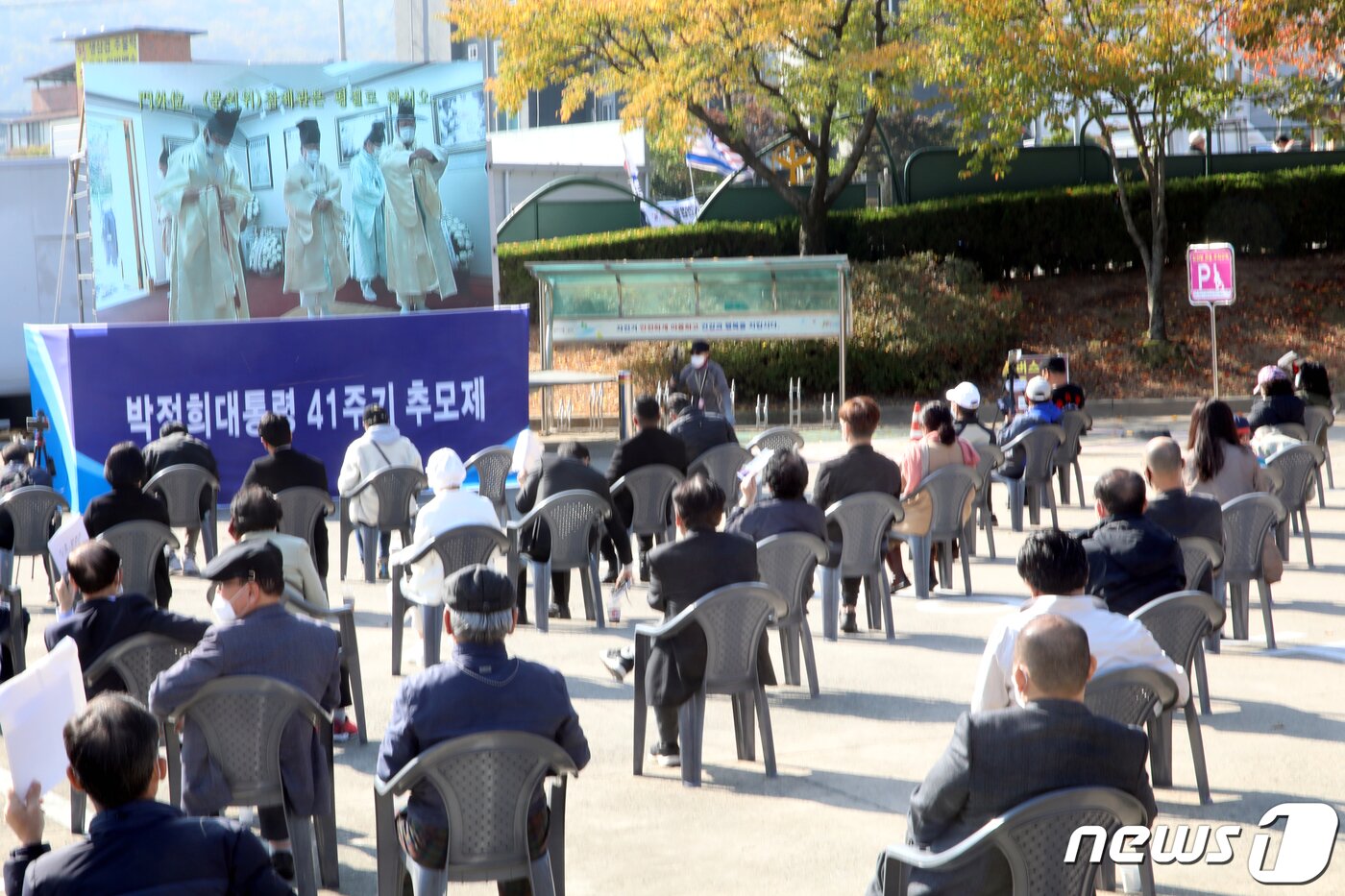 본문 이미지 - 26일 경북 구미시 박정희 생가에서 열린 박 전 대통령 41주기 추모식에 참석한 추모객들이 야외주차장에 마련된 대형스크린으로 추모식 장면을 지켜보고 있다. 이날 추모식은 코로나19로 추도식은 하지 않고 헌관들도 추모관 밖에서 대기하다가 제례때만 입장했고 추모객들은 야외 주차장에 마련된 대형 스크린으로 추모행사를 지켜본 후 제례가 끝난 후 헌화했다. 2020.10.26 뉴스1 ⓒ News1 정우용 기자