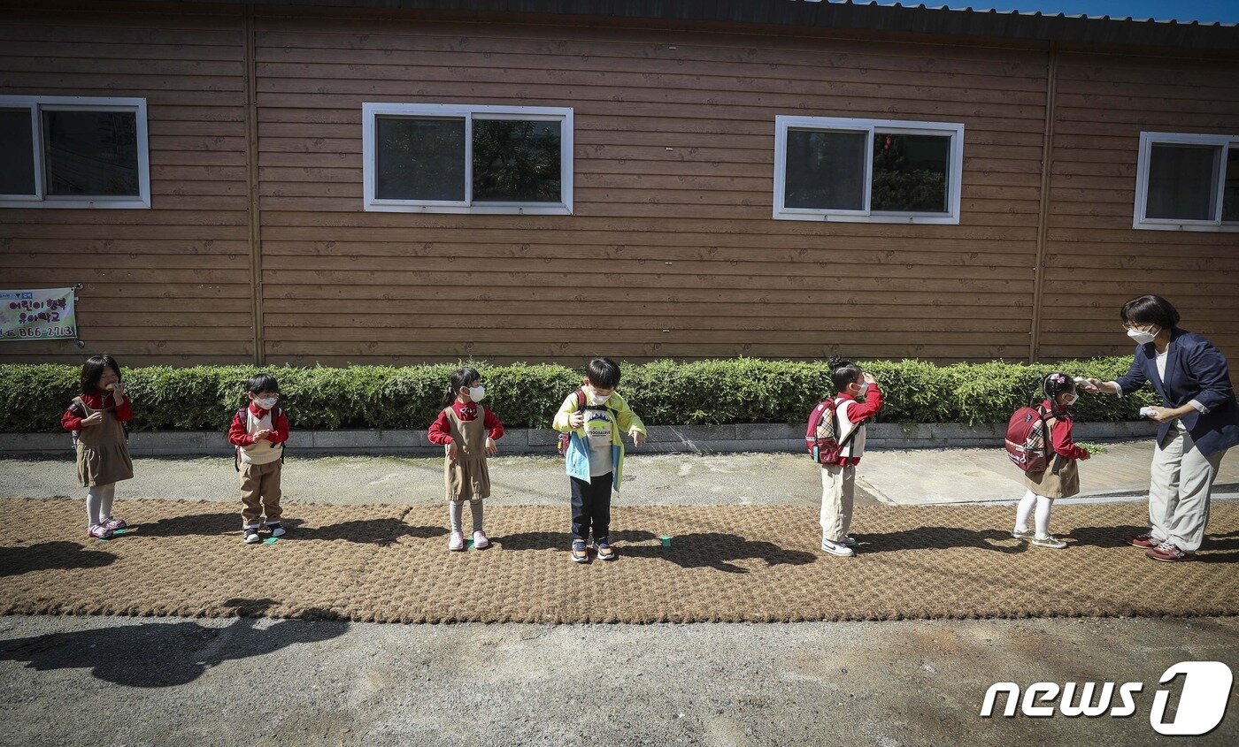 본문 이미지 - 코로나19 부문 최우수상 수상작인 '낯선 거리두기'(이기범作). 유치원에 등원한 아이들이 거리두기를 지키며 발열체크와 손소독을 하고 있는 모습을 담았다.ⓒ 뉴스1
