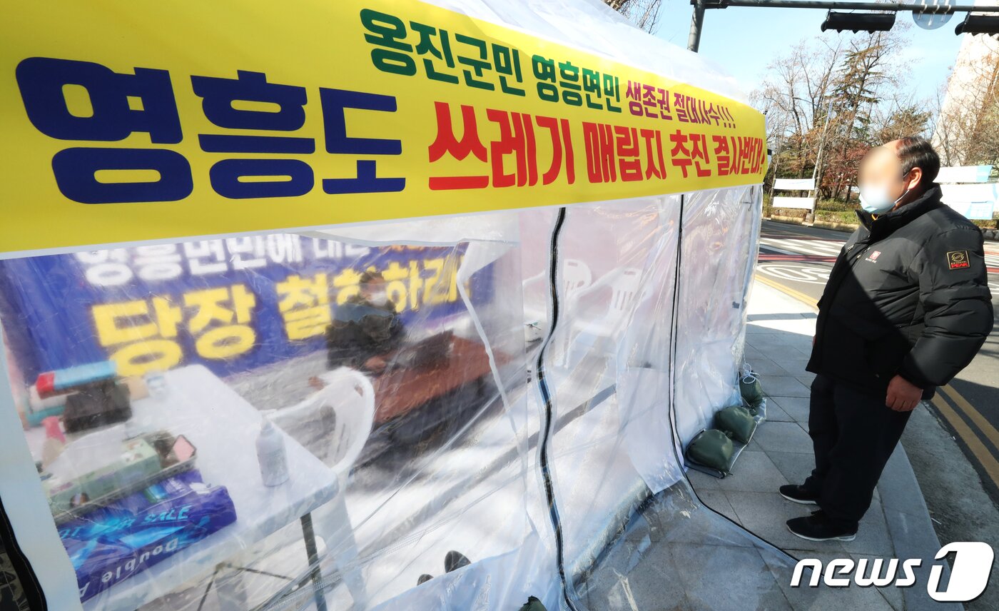 본문 이미지 - 장정민 인천 옹진군수가 1일 오후 인천시 남동구 인천시청 앞에 설치된 천막에서 영흥도 폐기물매립지 조성 계획에 반발하며 단식농성을 벌이고 있는 가운데 한 시민이 장 군수를 바라보고 있다. 인천시는 2025년 수도권매립지 사용 종료에 따라 2024년까지 1400억원을 투입해 옹진군 영흥면에 에코랜드를 조성한 뒤 이곳에 인천 생활폐기물 소각재와 불연성 폐기물 매립 계획을 발표했다. 2020.12.1/뉴스1 ⓒ News1 정진욱 기자