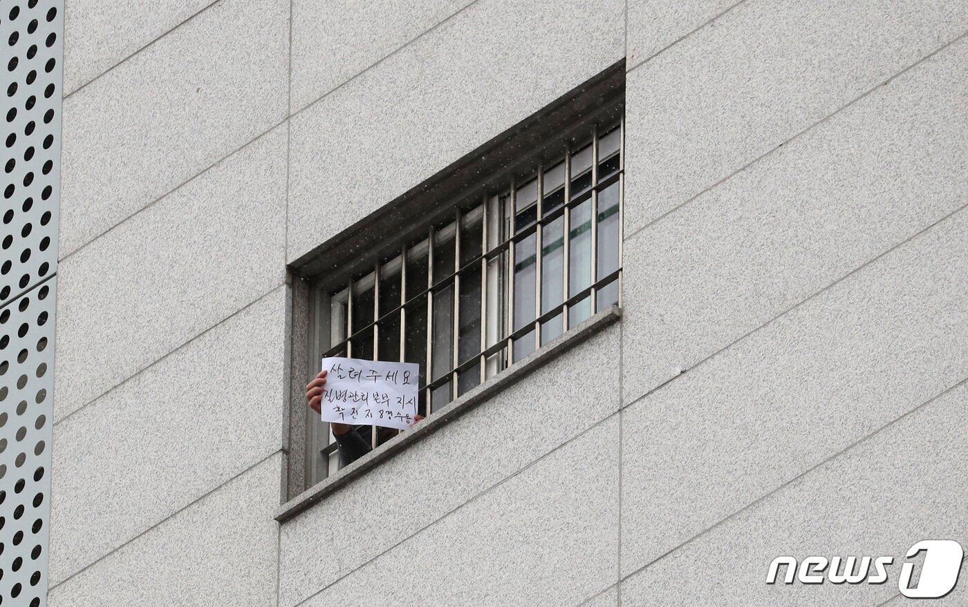 본문 이미지 - 대규모 집단감염이 발생한 서울 동부구치소에서 233명이 추가 확진되면서 누적 확진자가 761명으로 집계된 29일 서울 송파구 동부구치소에서 한 수용자가 자필로 '살려주세요'라고 쓴 문구를 취재진에게 보여주고 있다. 2020.12.29/뉴스1 ⓒ News1 이성철 기자