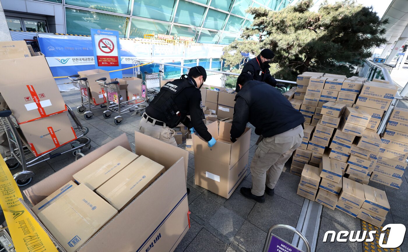 본문 이미지 - 2월 6일 오전 인천국제공항 여객터미널 출국장 입구에 마스크 박스가 쌓여있는 가운데 인천공항 경비 관계자들이 마스크를 유실물센터로 옮기고 있다. 앞서 인천공항경찰단은 5일 마스크를 택배 상자에 옮긴(박스갈이)한 홍콩인 A씨를 조사했다. 현장에서 A씨가 옮겨 담고 있던 마스크는 1만여개가 넘는 것으로 확인됐다.2020.2.6/뉴스1 ⓒ News1 정진욱 기자