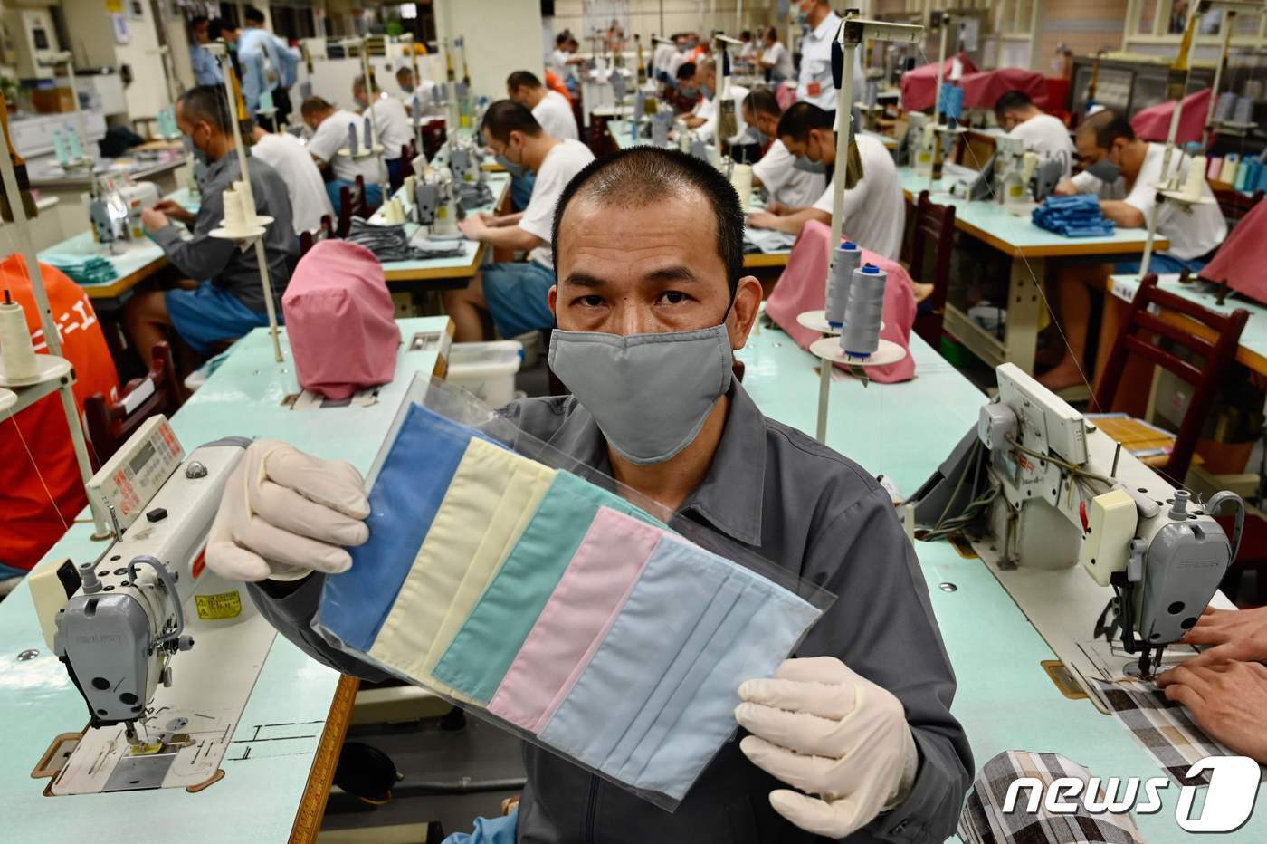 본문 이미지 - 한 재소자가 자신이 제작한 형형색색 마스크 제품을 들어 보이고 있다. 이것이 'Made in 교도소' 특별 마스크다. ⓒ AFP=뉴스1