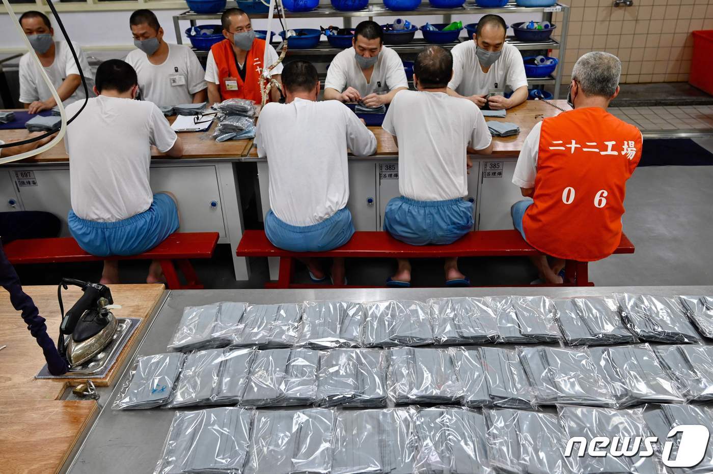 본문 이미지 - 마스크를 만드는 재소자들 뒤편으로 포장된 완성품들이 보인다. ⓒ AFP=뉴스1