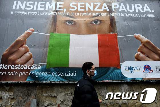 이탈리아 나폴리 거리에서 한 남성이 코로나-19의 확산에 맞서기 위해 이탈리아 정부가 제작한 대형 광고판 앞을 지나가고 있다. © AFP=뉴스1 