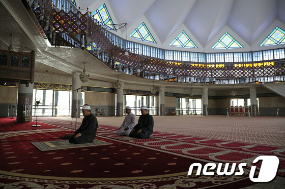 말레이시아 국립 모스크의 이맘이 코로나 우려로 금요 기도회가 금지돼 텅 빈 경내에서 기도를 올리고 있다. © 로이터=뉴스1