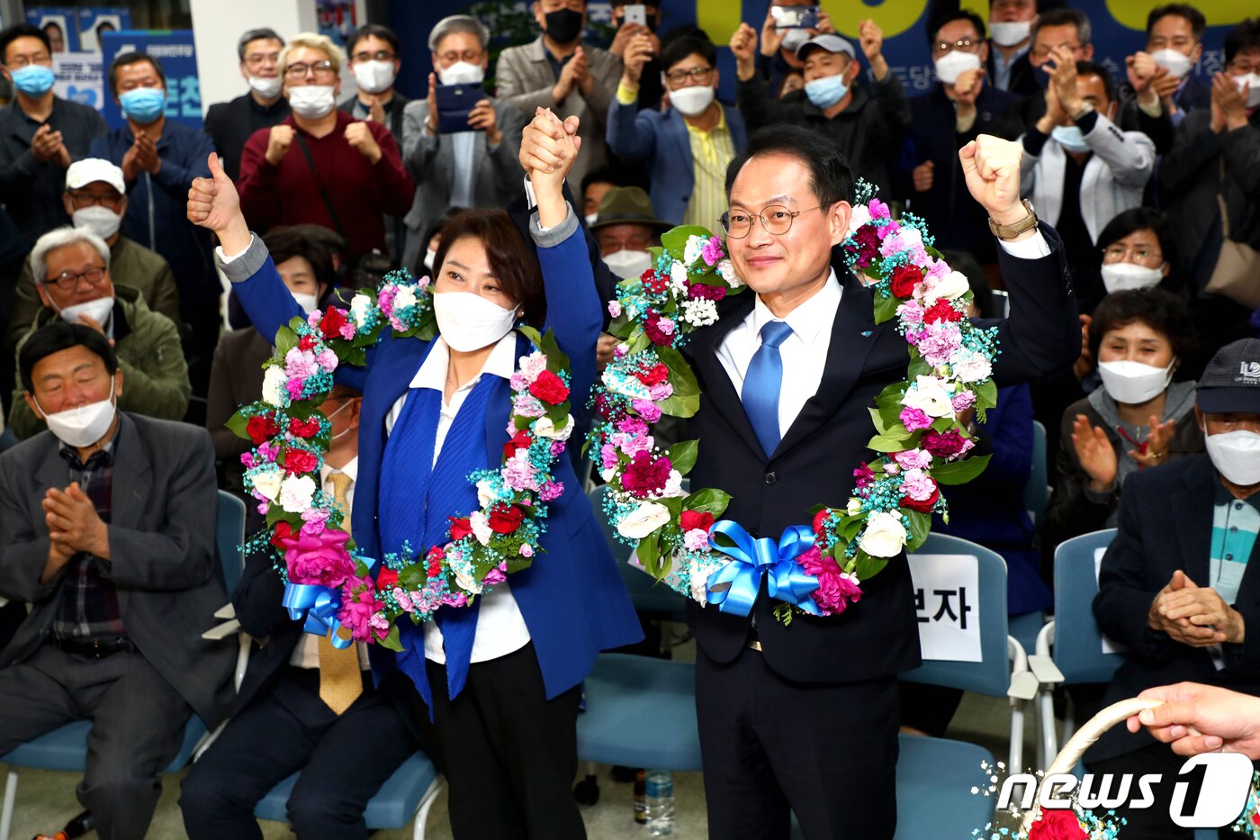 본문 이미지 - 제21대 총선 춘천·철원·화천·양구갑 선거구에 출마한 더불어민주당 허영 후보(오른쪽)가 16일 오전 자신의 선거캠프에서 당선이 확실시되자 꽃목걸이를 걸고 배우자 정현자씨와 손을 맞잡아 들며 기뻐하고 있다. 2020.4.16/뉴스1 ⓒ News1 김경석 기자
