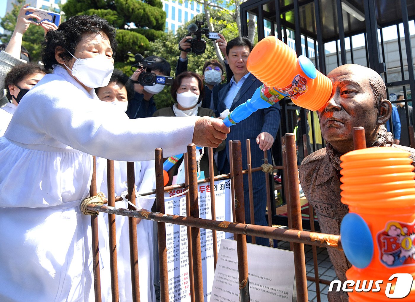 본문 이미지 - 5.18 헬기사격을 증언한 고&#40;故&#41; 조비오 신부에 대한 사자명예훼손 혐의로 재판을 받는 전두환 씨가 법정에 출석하는 27일 광주 동구 광주지법 앞에서 오월 어머니회 회원이 무릎 꿇은 전두환 동상을 때리고 있다. 2020.4.27/뉴스1 ⓒ News1 황희규 기자