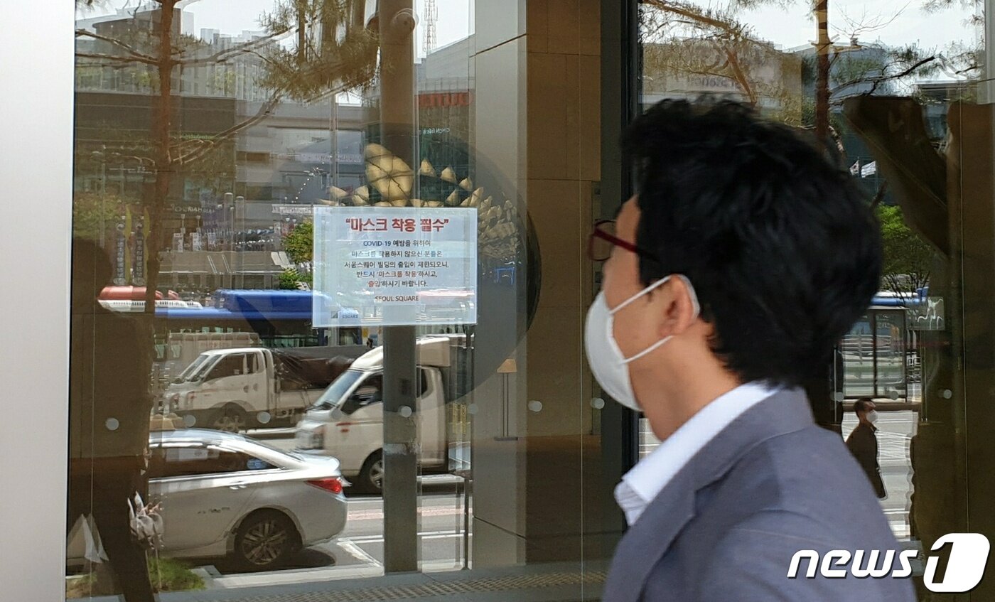 본문 이미지 - 11일 한 시민이 서울 중구 서울스퀘어 건물 유리벽에 붙은 마스크 착용 안내문을 보고 있다. 서울스퀘어는 지난 10일 한 입주업체 직원이 신종 코로나바이러스(코로나19) 확진 판정을 받았다는 통보를 받고 건물 10층과 식당가를 폐쇄했다.2020.5.11/뉴스1ⓒ 뉴스1 이비슬 기자ⓒ 뉴스1
