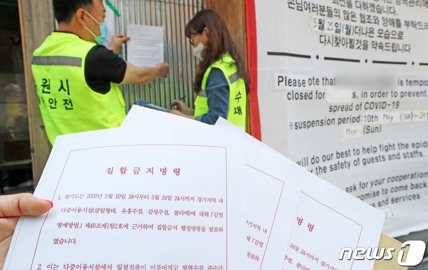 본문 이미지 - 경기 수원시청 관계자들이 인계동의 한 감성주점 출입구에 신종 코로나바이러스 감염증(코로나19) 확산 방지를 위한 집합금지명령서를 부착하고 있다. 2020.5.11/뉴스1 