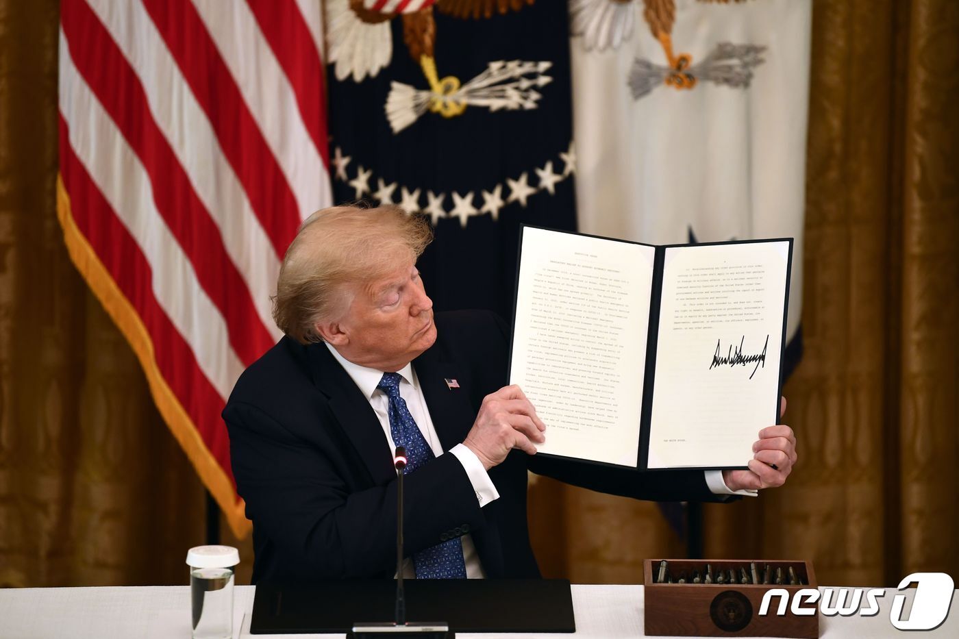 본문 이미지 - 트럼프 대통령이 지난 19일 백악관에서 서명한 경제 재개를 위한 행정명령을 들어보이고 있다. ⓒ AFP=뉴스1 ⓒ News1 