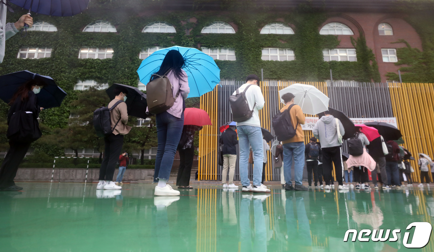 (서울=뉴스1) 송원영 기자 = 24일 서울 성북구 서경대학교에서 열린 SK 그룹 상반기 공채 필기전형인 SK종합역량검사(SKCT)에서 우산을 쓴 수험생들이 거리를 두고 시험에 참 …