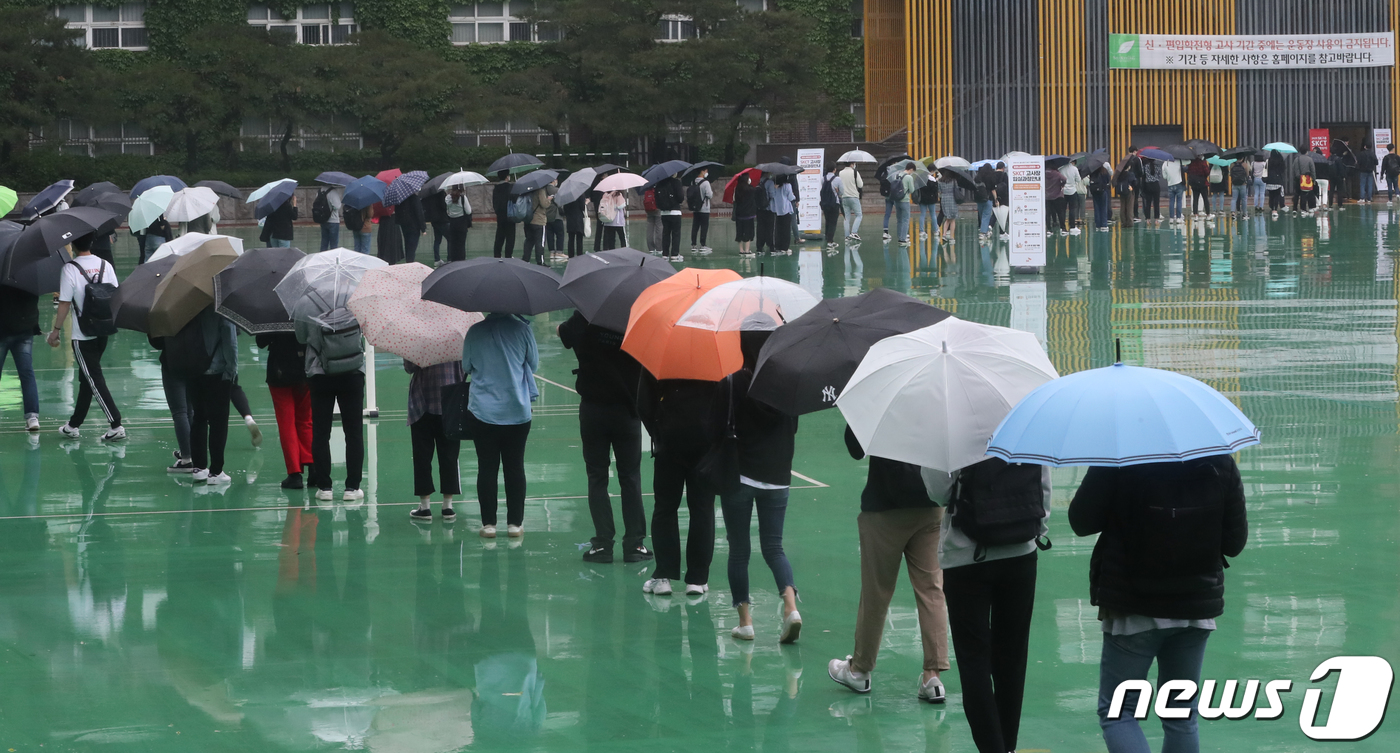 (서울=뉴스1) 송원영 기자 = 24일 서울 성북구 서경대학교에서 열린 SK 그룹 상반기 공채 필기전형인 SK종합역량검사(SKCT)에서 우산을 쓴 수험생들이 거리를 두고 시험에 참 …