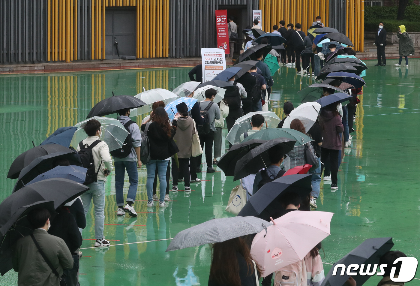 (서울=뉴스1) 송원영 기자 = 24일 서울 성북구 서경대학교에서 열린 SK 그룹 상반기 공채 필기전형인 SK종합역량검사(SKCT)에서 우산을 쓴 수험생들이 거리를 두고 시험에 참 …