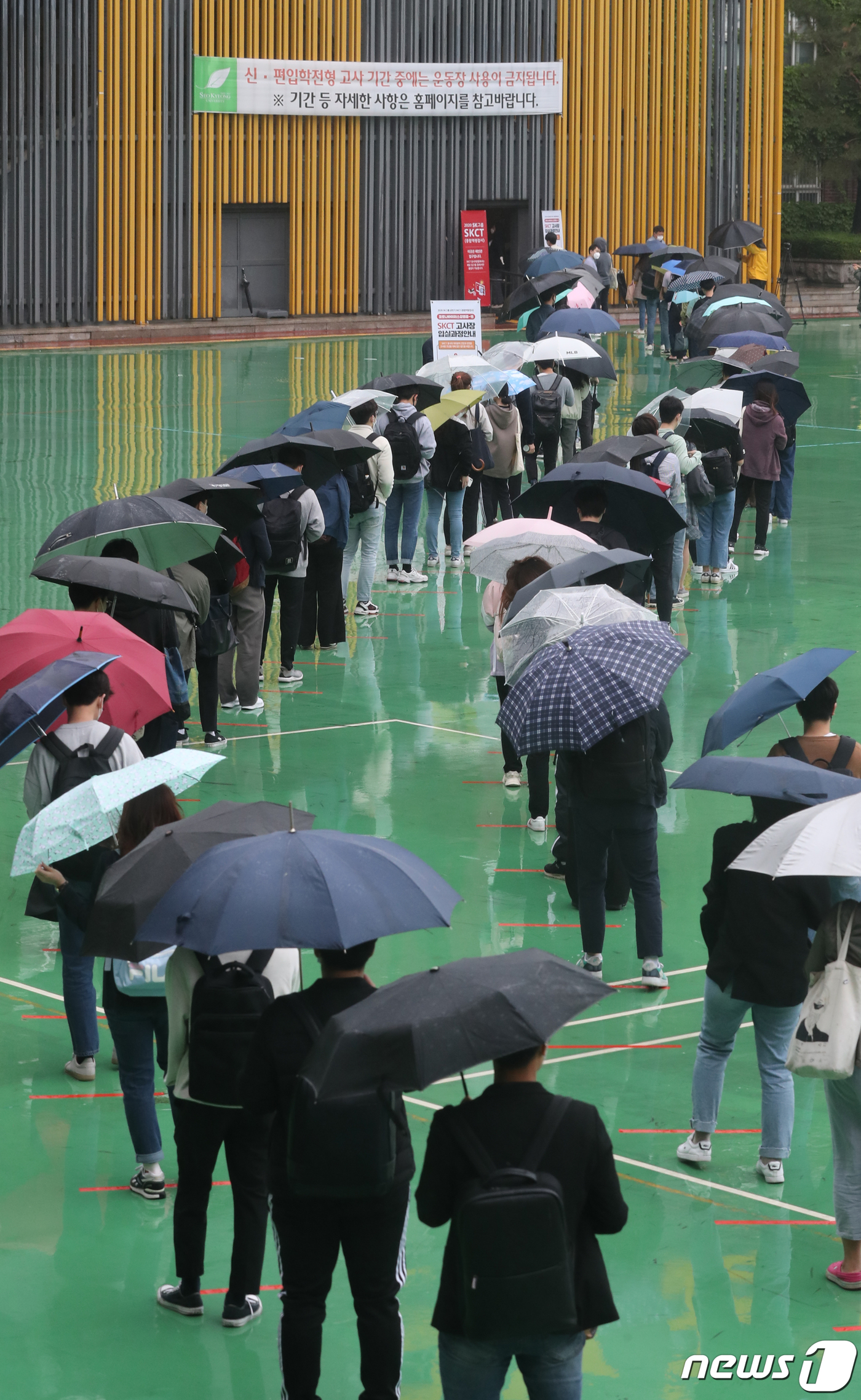 (서울=뉴스1) 송원영 기자 = 24일 서울 성북구 서경대학교에서 열린 SK 그룹 상반기 공채 필기전형인 SK종합역량검사(SKCT)에서 우산을 쓴 수험생들이 거리를 두고 시험에 참 …