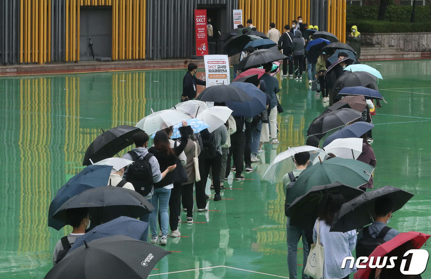 (서울=뉴스1) 송원영 기자 = 24일 서울 성북구 서경대학교에서 열린 SK 그룹 상반기 공채 필기전형인 SK종합역량검사(SKCT)에서 우산을 쓴 수험생들이 거리를 두고 시험에 참 …