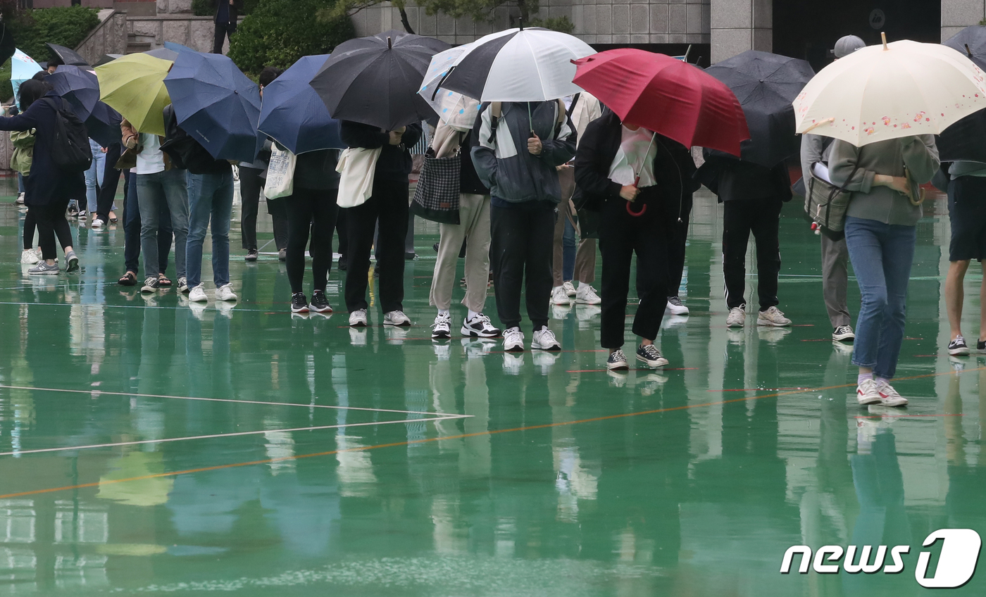 (서울=뉴스1) 송원영 기자 = 24일 서울 성북구 서경대학교에서 열린 SK 그룹 상반기 공채 필기전형인 SK종합역량검사(SKCT)에서 우산을 쓴 수험생들이 거리를 두고 시험에 참 …