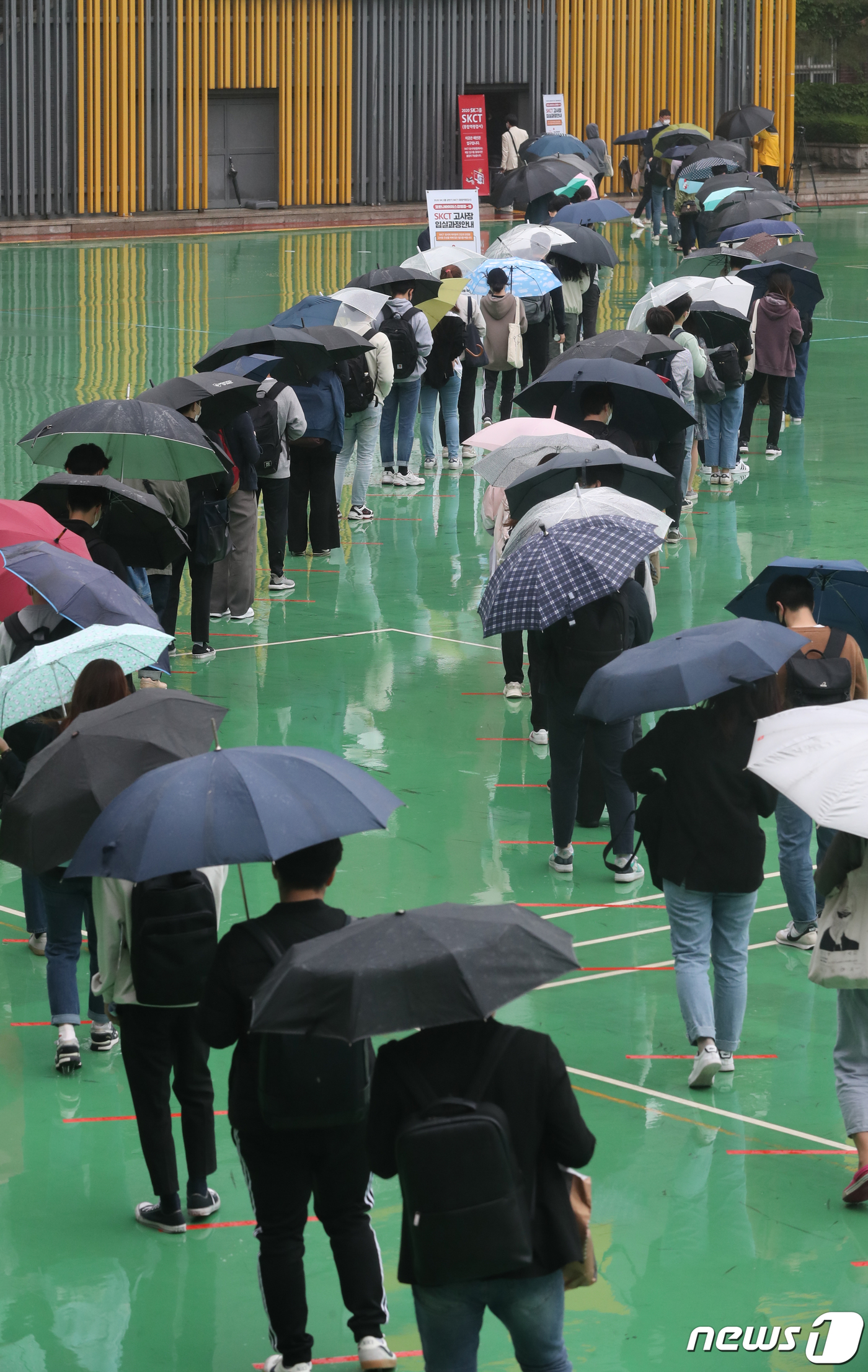 (서울=뉴스1) 송원영 기자 = 24일 서울 성북구 서경대학교에서 열린 SK 그룹 상반기 공채 필기전형인 SK종합역량검사(SKCT)에서 우산을 쓴 수험생들이 거리를 두고 시험에 참 …