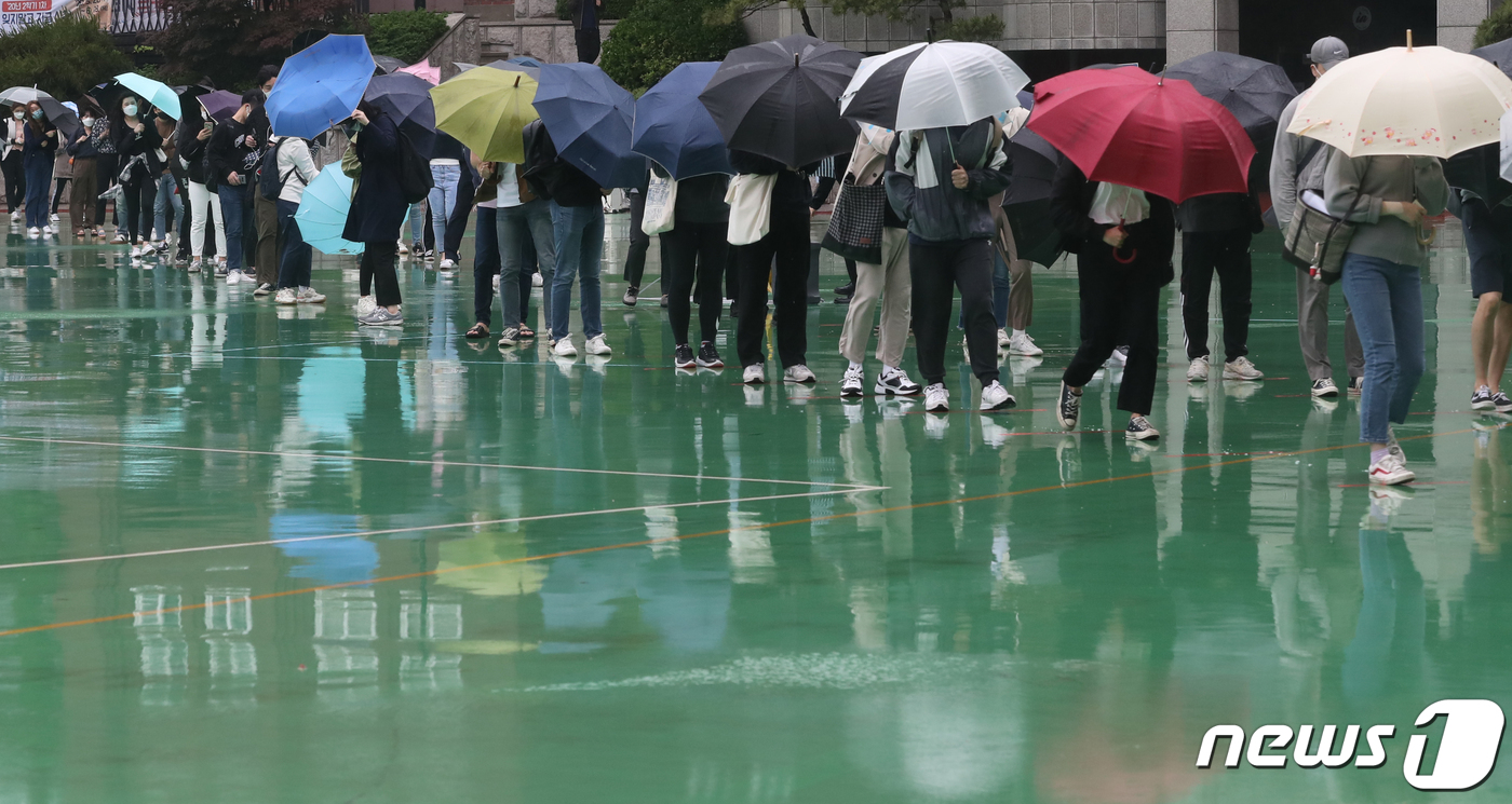 (서울=뉴스1) 송원영 기자 = 24일 서울 성북구 서경대학교에서 열린 SK 그룹 상반기 공채 필기전형인 SK종합역량검사(SKCT)에서 우산을 쓴 수험생들이 거리를 두고 시험에 참 …
