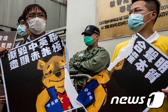 24일 주홍콩 연락팡공실 앞에서 열린 홍콩 국가보안법 반대 시위 도중 홍콩 시위대가 시진핑 중국 국가주석을 상징하는 곰돌이 푸 플래카드를 찢고 있다. © AFP=뉴스1