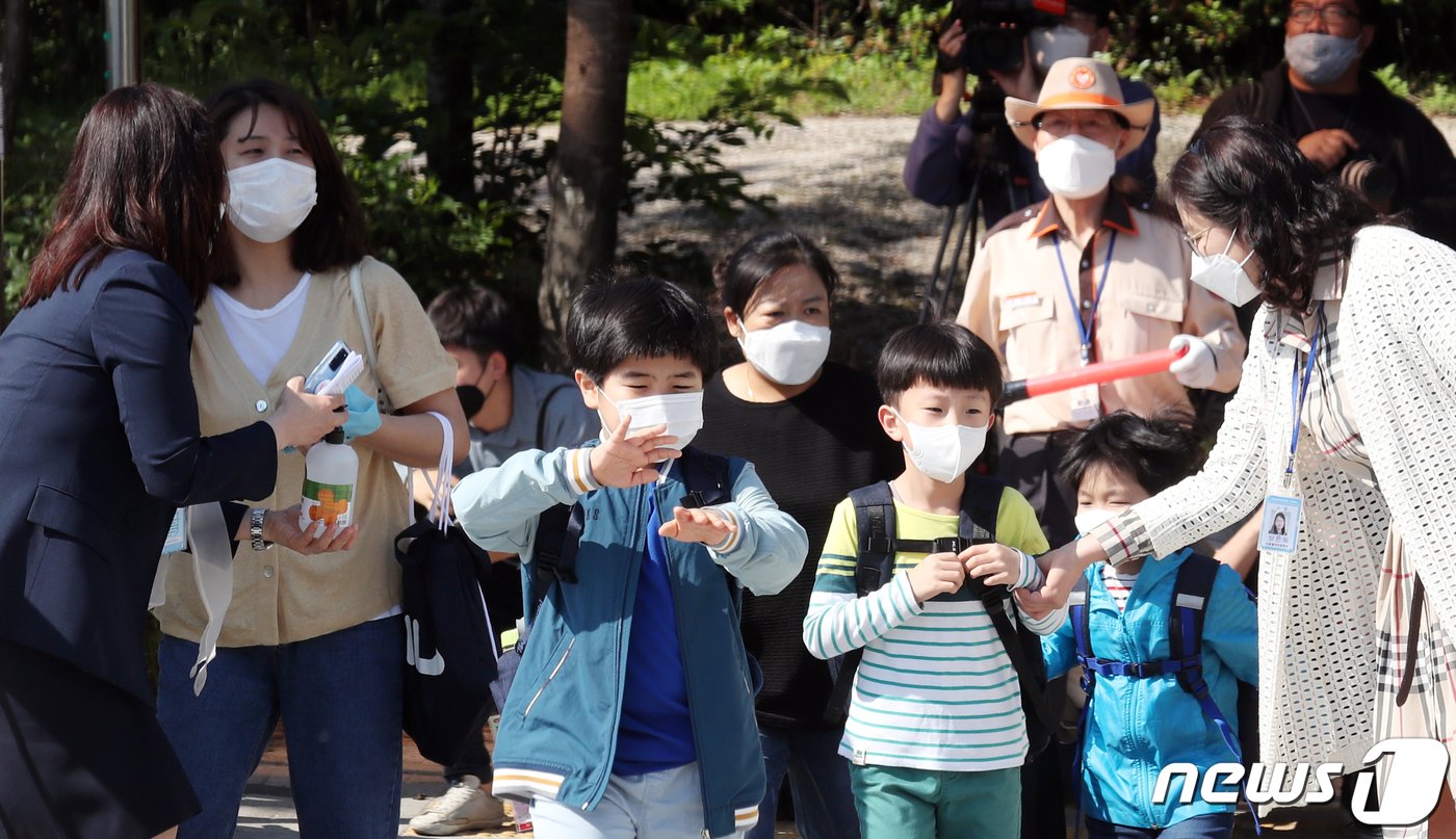 초등학교 1~2학년 학생과 엄마가 27일 서울 성북구 월곡초등학교에서 등교하며 인사를 하고 있다. 이날 초등 1~2학년과 유치원생, 고등학교 2학년, 중학교 3학년이 예정대로 등교수업을 시작한다. 등교를 하루 앞두고 교사와 학생이 잇따라 신종 코로나바이러스 감염증&#40;코로나19&#41; 확진판정을 받으면서 최소 453개 학교가 등교를 연기하는 등 학부모 불안감은 커지고 있다. 2020.5.27/뉴스1 ⓒ News1 김명섭 기자