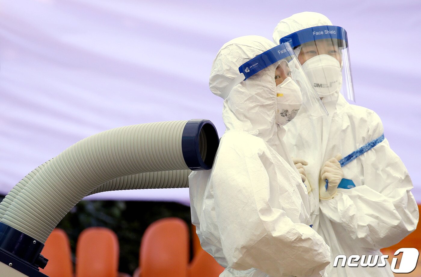 본문 이미지 - 지난 14일 서울 강서구 보건소 신종 코로나바이러스 감염증(코로나19) 선별진료소에서 방호복을 입은 의료진이 아이스 스카프를 두르고 냉방 장치 앞에서 더위를 식히고 있다./뉴스1 ⓒ News1