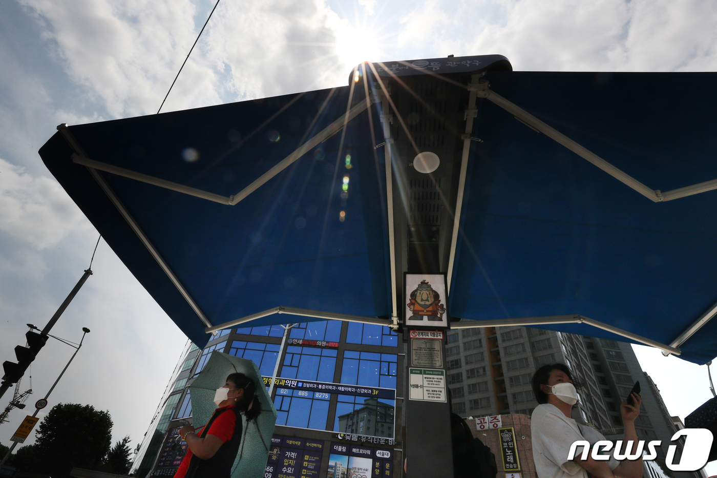 (서울=뉴스1) 황기선 기자 = 19일 서울 관악구 서울대입구역 앞에 설치된 '강감찬 스마트 그늘막'에서 시민들이 햇빛을 피하고 있다.'강감찬 스마트 그늘막'은 사물인터넷(IoT) …