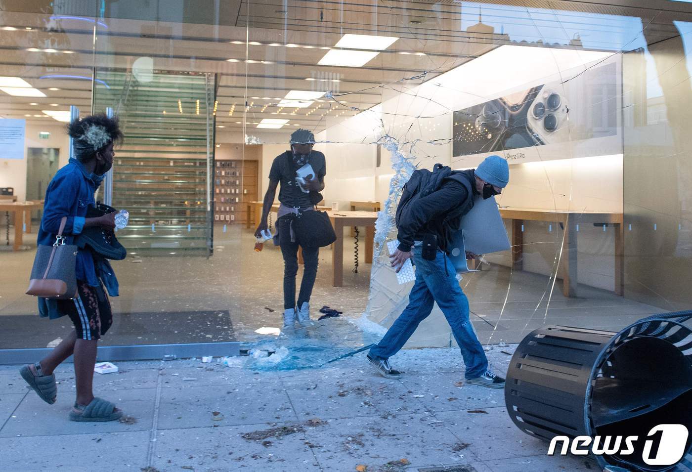 본문 이미지 - 지난달 30일 미국 로스앤젤레스의 한 쇼핑센터에서 얼굴을 가린 사람들이 애플스토어 문을 깨고 들어가 물건을 가져가고 있다. ⓒ AFP=뉴스1