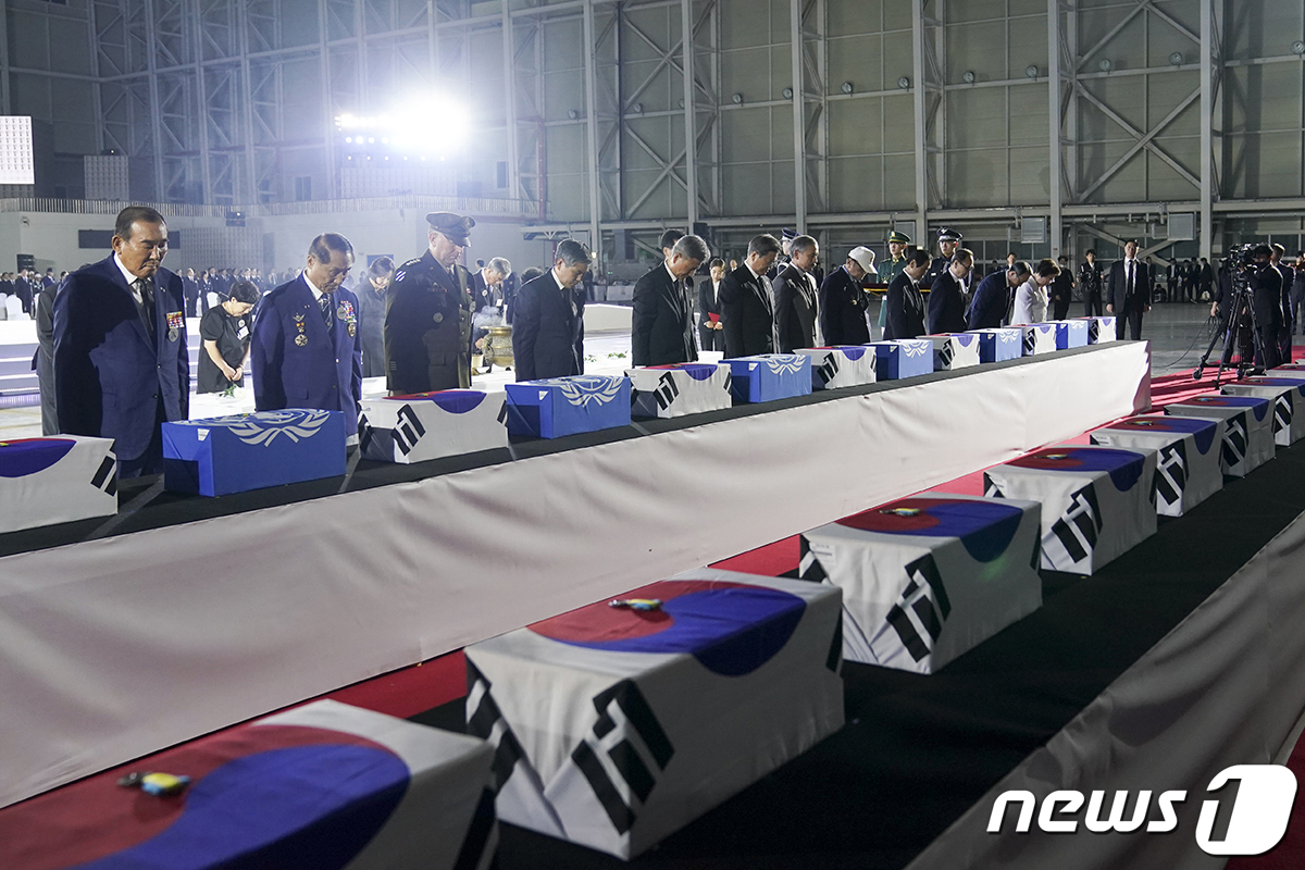 (서울=뉴스1) = 문재인 대통령이 25일 경기 성남 서울공항에서 열린 6.25전쟁 70주년 행사에서 국군 전사자들의 유해함에 참전기장을 수여한뒤 참석자들과 묵념하고 있다.(청와대 …