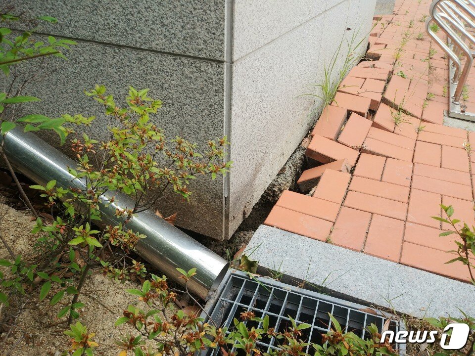 본문 이미지 - 3일 오전 11시15분쯤 부산 강서구 송정동 녹산금융공단 안에 있는 지상 2층 규모의 경남은행 녹산지점 건물과 주차장에서 지반 침하 현상이 나타나 직원들이 대피하는 소동이 벌어졌다. 땅이 꺼지면서 건물 주변에 깔린 블럭과 시설물이 파손된 모습.(부산소방재난본부 제공)ⓒ 뉴스1