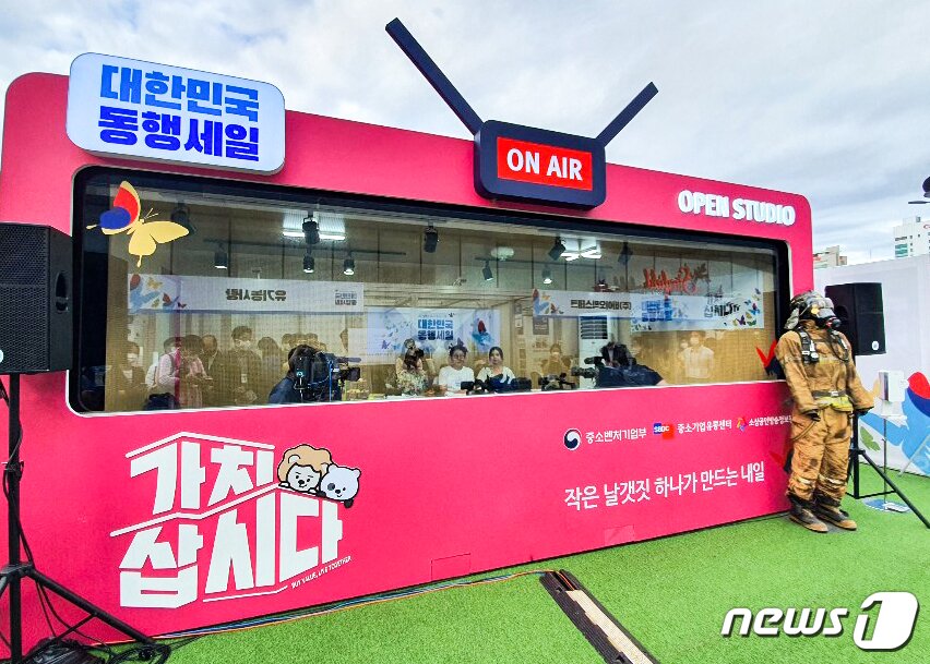 본문 이미지 - 조명래 환경부 장관이 10일 서울 강남구 코엑스에서 열린 대한민국 동행세일 라이브 커머스 방송에 출연해 업사이클 기업 ‘119레오 주식회사’의 레코백(REO+ECOBAG, 소방관의 방화복을 업사이클한 제품)과 ‘우시산’의 반구대암각화티셔츠(폐페트병에서 뽑아낸 재생폴리에스테르 섬유로 만든 제품)를 소개하고 있다.