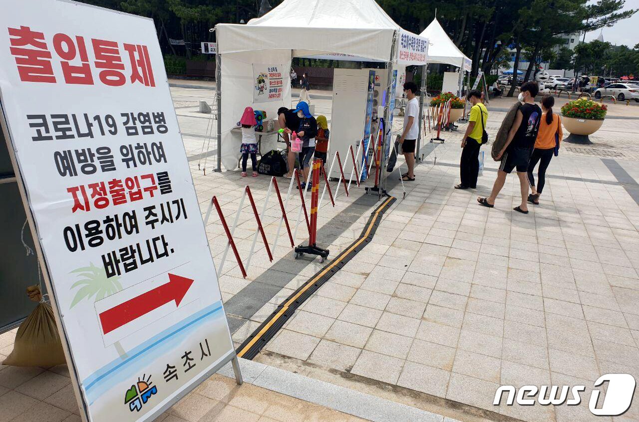 본문 이미지 - 동해안 일부 해수욕장 개장 후 첫 주말인 지난 12일 강원 속초시 속초해수욕장 입구에 설치된 게이트형 방역기를 피서객들이 줄을 서서 통과하고 있다./뉴스1 ⓒ News1 최석환 기자