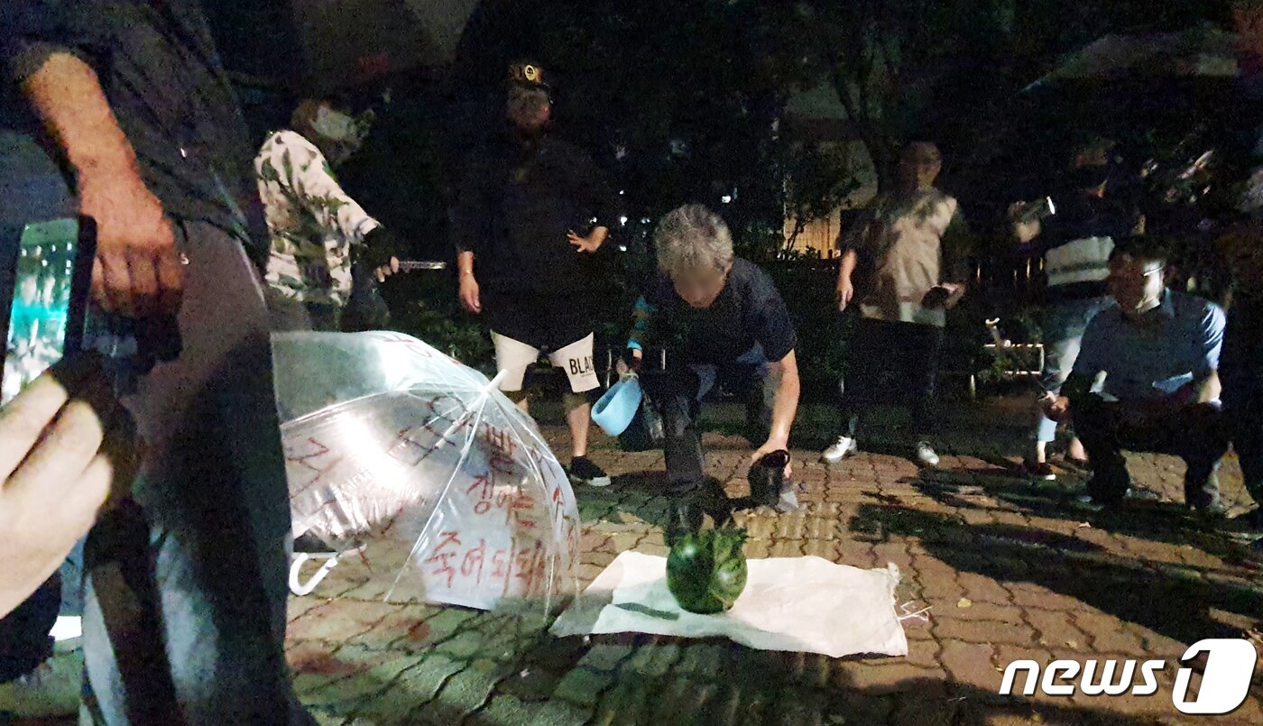 본문 이미지 - 문재인 대통령을 향해 신발을 벗어 던진 뮤지컬 극단 '긍정의 힘' 정창옥 단장(57)이 19일 오후 법원의 영장이 기각되면서 서울 영등포경찰서 유치장을 나와 신발로 수박을 깨는 퍼포먼스를 하고 있다. 2020.7.19/뉴스1 ⓒ News1 황덕현 기자