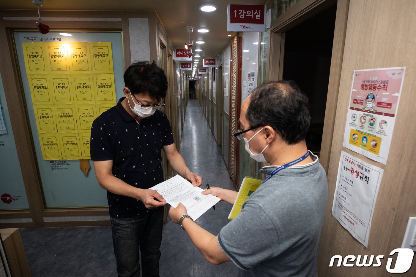 본문 이미지 - 19일 서울 양천구 목동의 한 학원에서 구청 관계자가 학원장에게 수도권 방역조치 강화에 따른 고위험시설 집합금지명령서를 전달하고 있다. ⓒ News1 유승관 기자