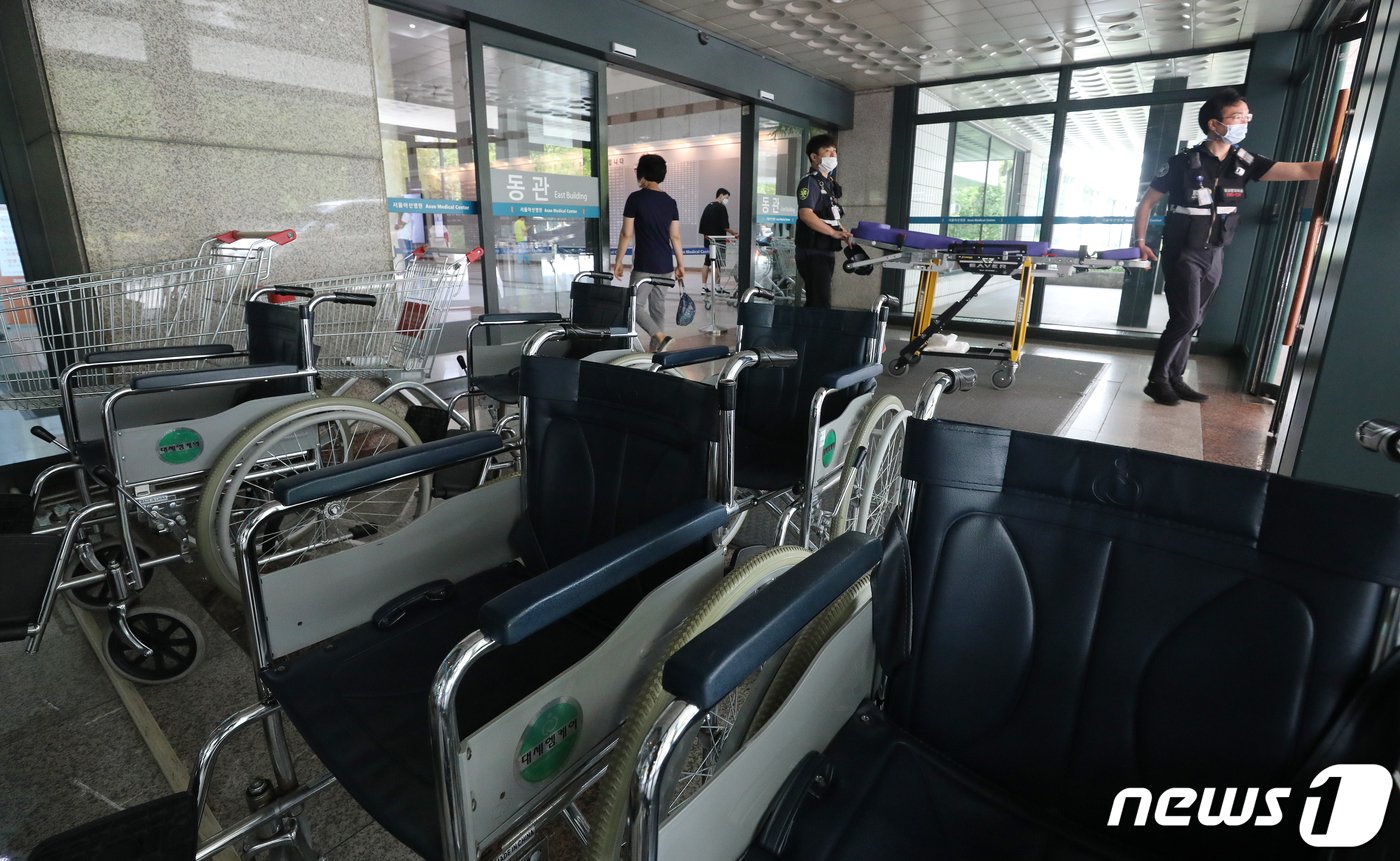 본문 이미지 - 전국의사 2차 총파업&#40;집단휴진&#41;에 돌입한 26일 오전 서울 송파구 아산병원 출입문 앞에 환자용 휠체어가 놓여 있다.. 대한의사협회는 예고대로 오늘부터 28일까지 사흘간 의대 정원 확대 등 의료정책에 반대하는 전국의사 2차 총파업에 돌입했다. 2020.8.26/뉴스1 ⓒ News1 김진환 기자