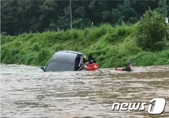 물에 떠내려오던 승용차서 구조되는 여성 운전자